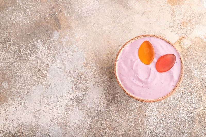 Purple Yogurt, with jelly candy on brown concrete background, top view, flat lay, copy space, minimalism