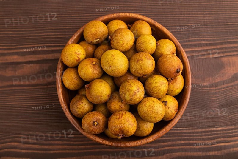 Ripe Longan in wooden bowl on brown wooden background, Top view, flat lay, close up, minimalism