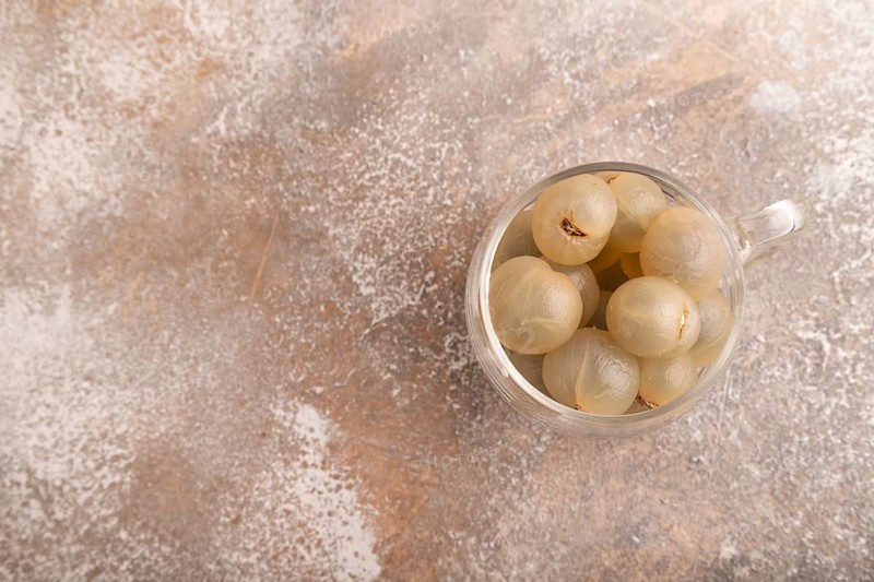 Ripe peeled Longan in glass on brown concrete background, top view, flat lay, copy space, minimalism