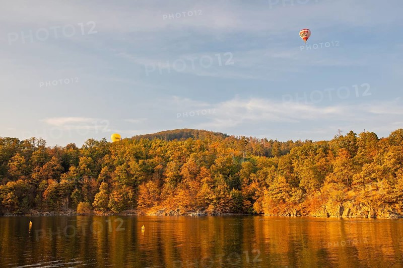 Hot air balloons over the Brno Reservoir (Brnenská prehrada) on the Svratka River on a sunny autumn day. The reservoir is located northwest of the city of Brno in the Czech Republic