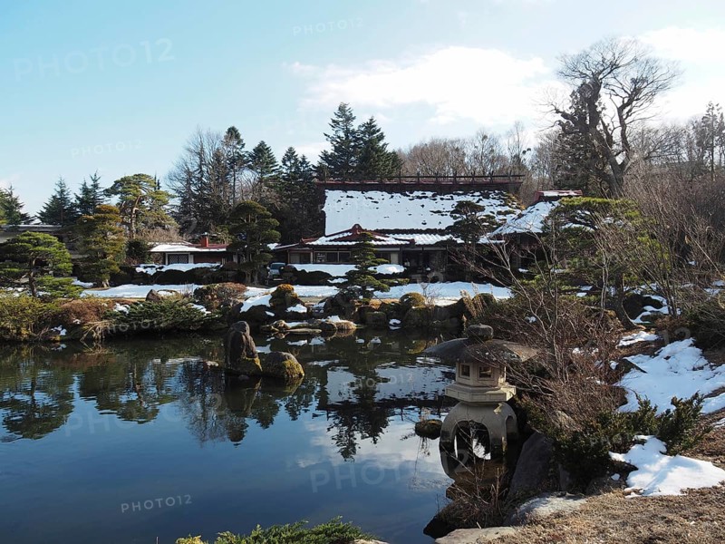 Snowy Japanese garden with small ponds and traditional buildings in the background, Oshino Hakkai, Kawaguchiko, Japan