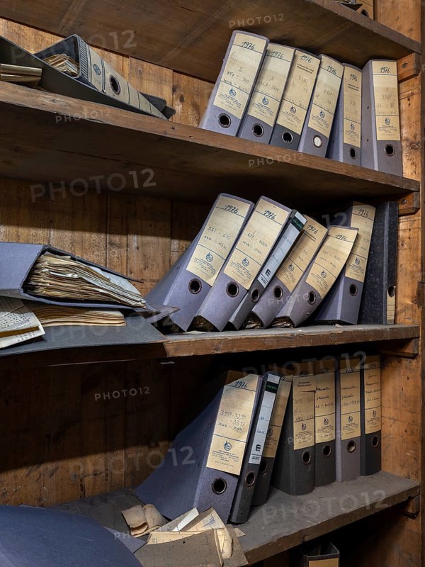 Shelves with dusty folders in the administration of a former GDR factory, Lost Place, Saxony-Anhalt, Germany