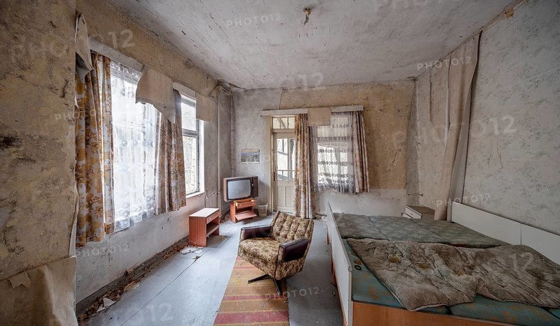 Abandoned hotel room with bed, armchair and television in a dilapidated hotel, Lost Place, Saxony-Anhalt, Germany
