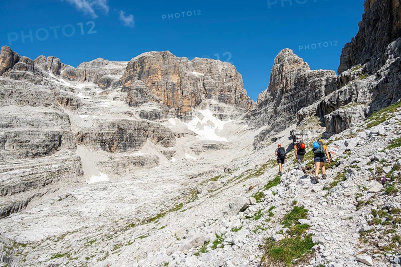 Hikers on hiking trail, behind Cima Margherita and Cima Tosa, Brenta Mountains, Brenta-Adamello Natural Park, Trentino, Italy
