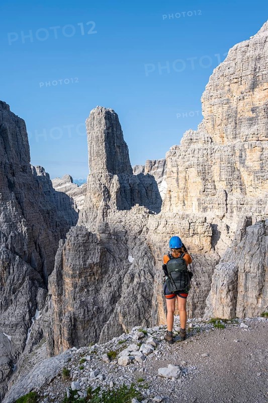 Female hiker in front of Campanile Alto and Cima Brenta Alta, Bocchette Centrale band trail, via ferrata in the Brenta Mountains, Parco Naturale Brenta-Adamello, Trentino, Italy