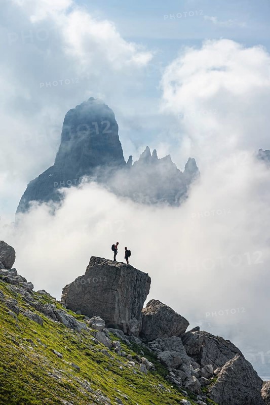 Alpine panorama, mountaineers on a large rock, fog and Torre Di Brentai and Cima Tosa, rocky mountain peaks and mountain landscape, Brenta Mountains, Parco Naturale Brenta-Adamello, Trentino, Italy