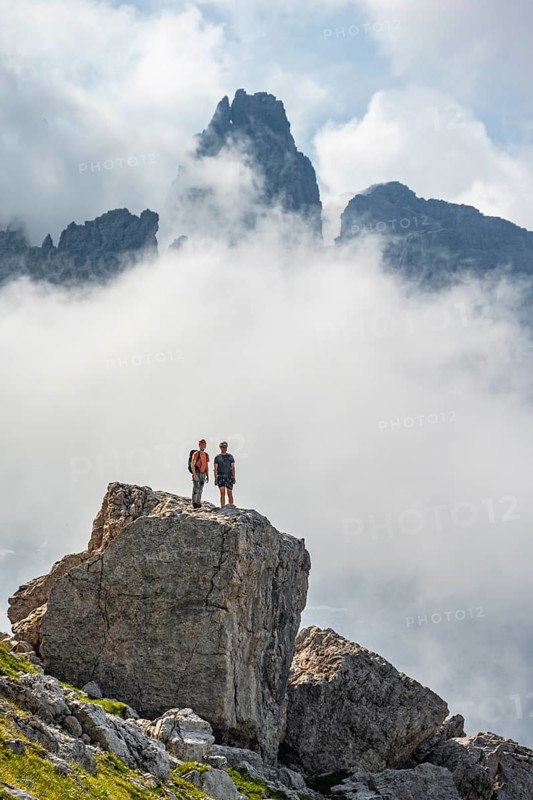 Mountaineers on a large rock, fog and Torre Di Brentai, rocky mountain peaks and mountain landscape, Brenta Mountains, Brenta-Adamello Natural Park, Trentino, Italy
