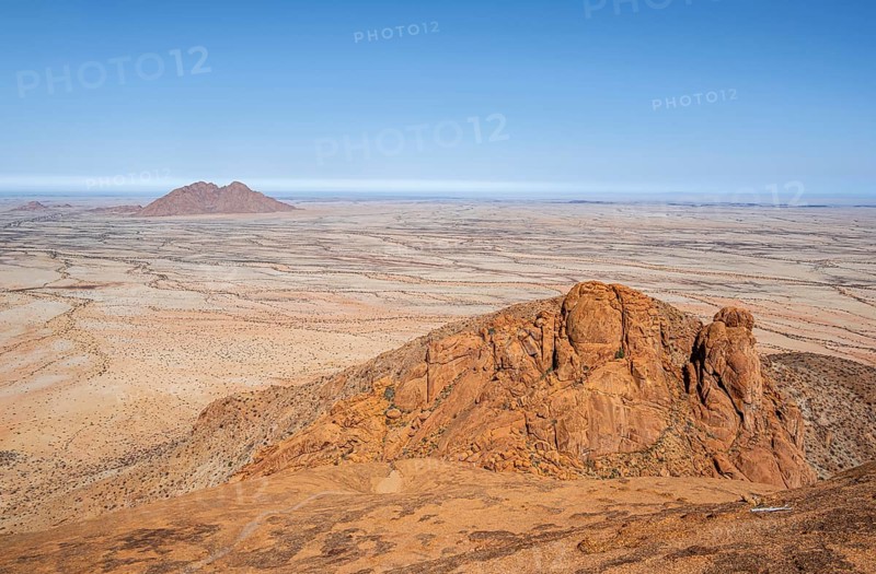 Red rocks against an endless desert landscape and blue sky in Spitzkoppe, Spitzkoppe, Namibia