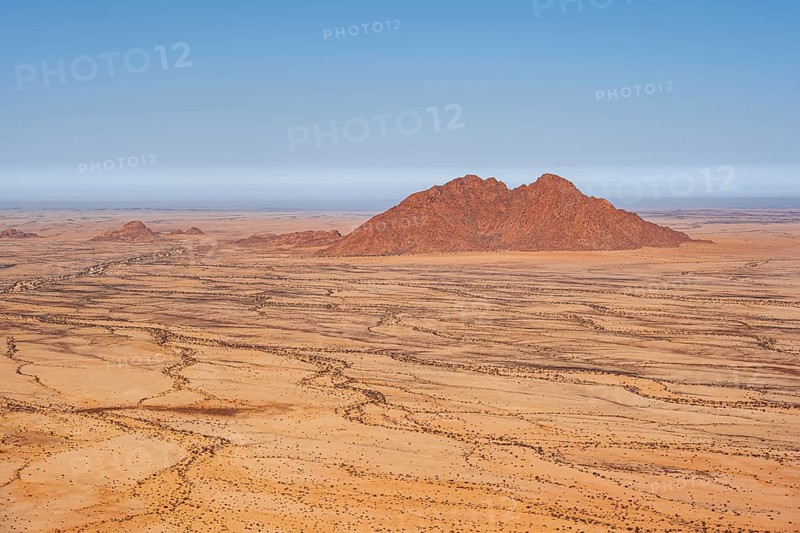 Silhouette of a rocky mountain in the middle of the vast, dry desert landscape, Spitzkoppe, Namibia