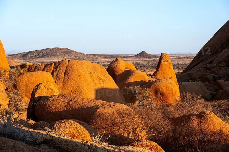 Rocks cast shadows over the dry landscape that stretches in the distance in the Spitzkoppe Desert, Spitzkoppe, Namibia