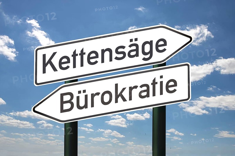 (Photo montage) Directional arrows against a blue sky with the inscription CHAINSAW and BUREAUCRACY