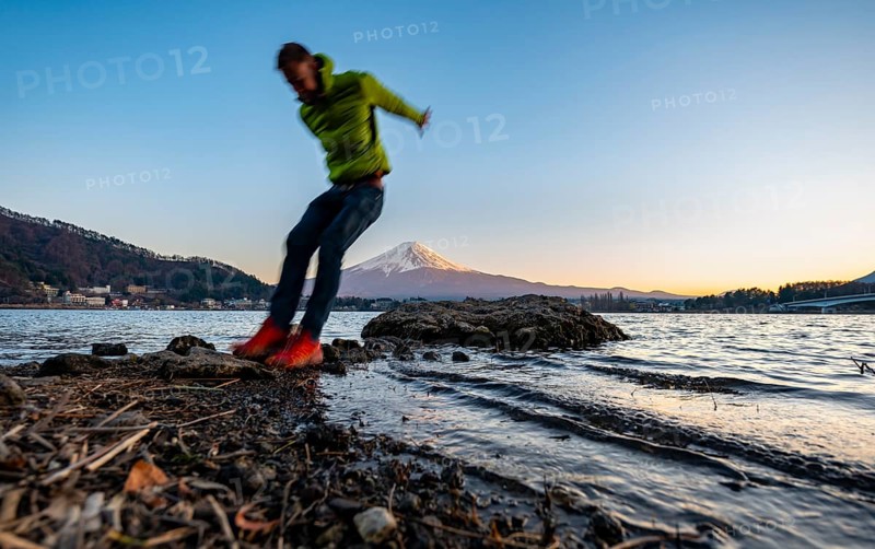 Young man jumping, Lake Kawaguchi, view of Mount Fuji volcano at sunset, Yamanashi Prefecture, Japan