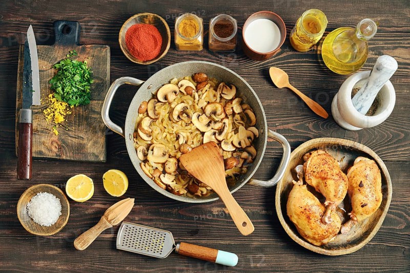 Chopped mushrooms and onion frying in a pan. Process of preparation of creamy mustard sauce for roasting chicken thighs with spices and lemon