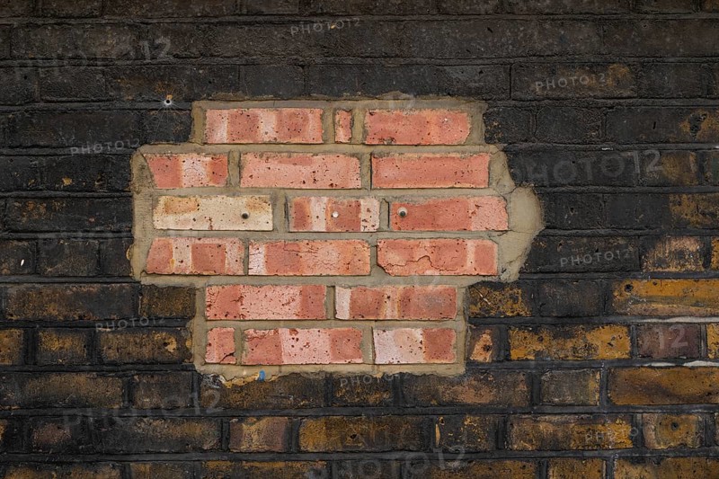 Partially repaired brick wall with contrast of old and new stones, London, England, Great Britain