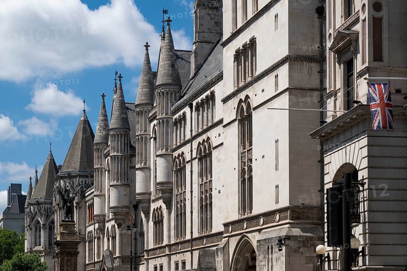 Royal Courts of Justice, neo-Gothic architecture with towers and British flag under blue sky, London, England, Great Britain