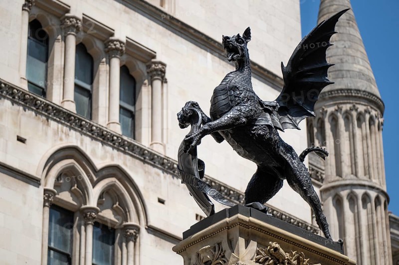 Metal statue of a winged dragon in front of the neo-Gothic building of the Royal Court of Justice, London, England, Great Britain