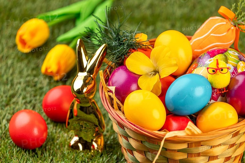 A basket with colorful eggs, flowers and Easter decoration in a meadow