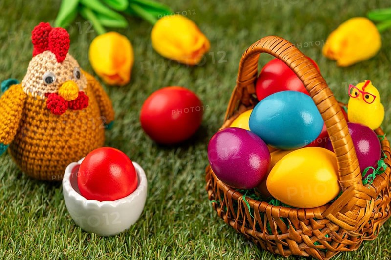 A basket of colorful Easter eggs next to a chicken figurine