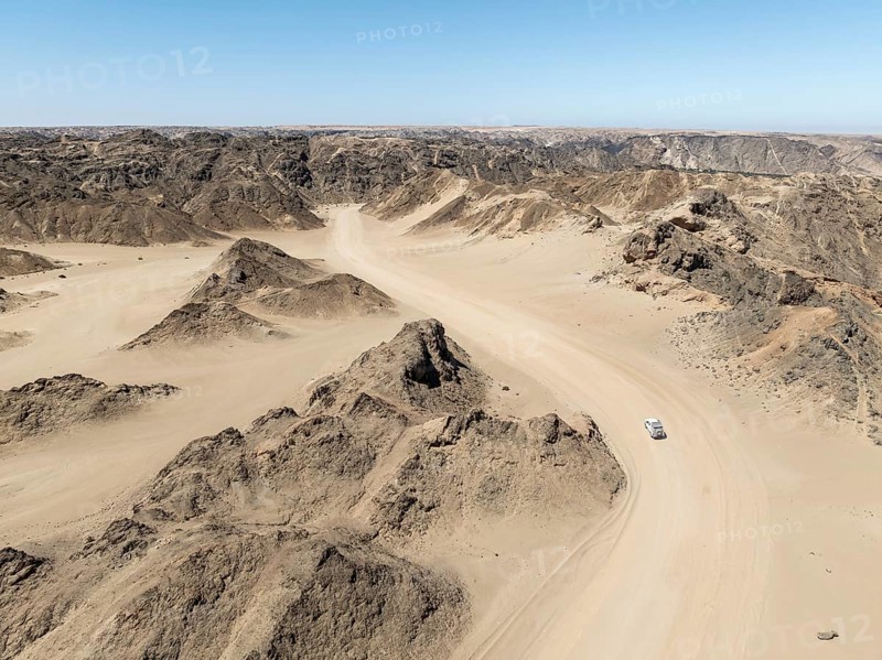 Aerial view, dry barren mountains in Moon Valley, road with car, rocky landscape ridged by erosion, Namib-Naukluft Park, Namib Desert, Namibia