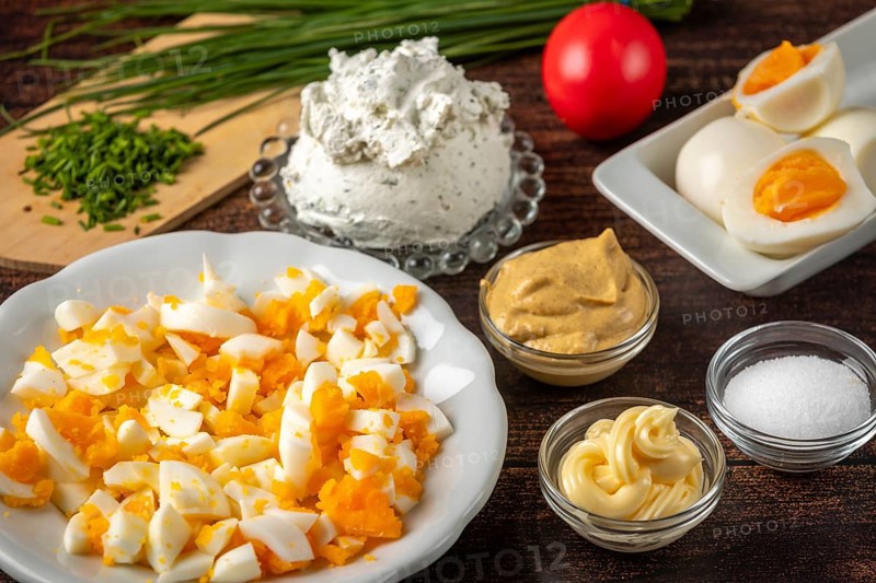 Ingredients for making egg cream with sliced eggs and cream cheese on a wooden table