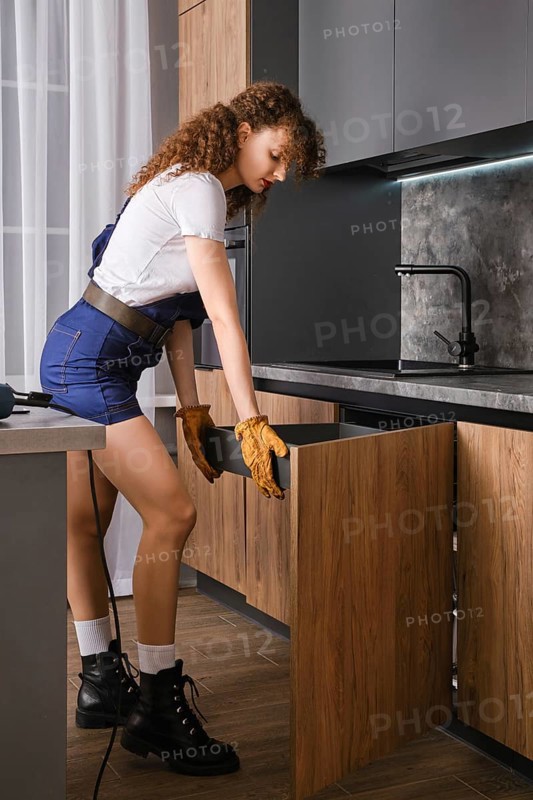 Young woman installing pull-out shelf in kitchen cabinet