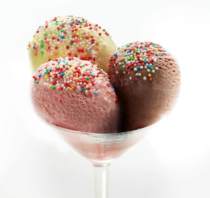 Ice cream sundae with chocolate, strawberry and vanilla, decorated with coloured sprinkles, studio shot against a white background