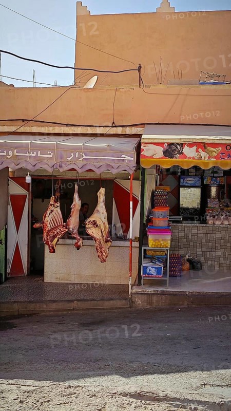Local butcher shop with hung meat in front of a traditional house in a market, southern Morocco