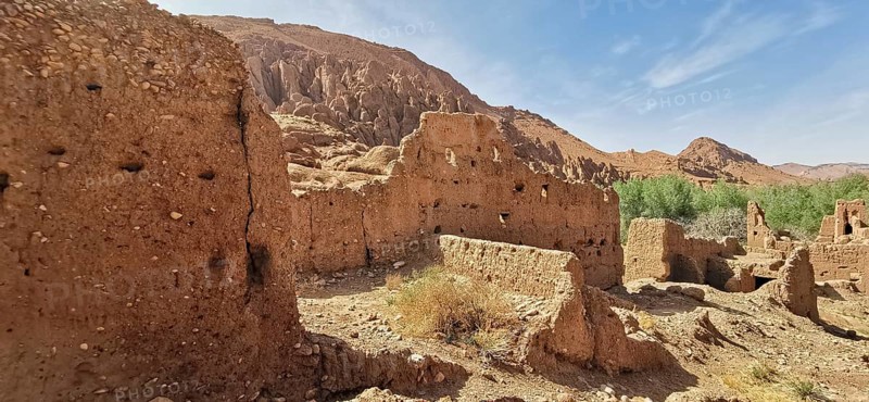 Ancient sandstone ruins in a dry, rocky landscape with sparse vegetation, Morocco