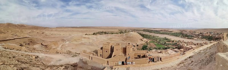 Historic buildings and an oasis in desert-like surroundings under cloudy skies, Morocco