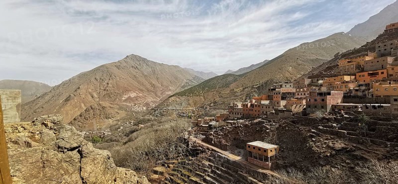 A rocky valley with a village in the mountains under cloudy sky, Atlas Mountains, Morocco
