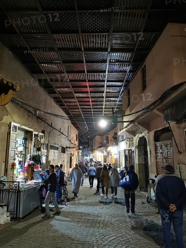 Bustling nocturnal alley in the Medina, with people under a covered path in an oriental market district, Marrakech, Morocco