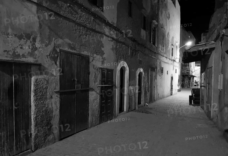 Nocturnal alley with old facades and closed door in a quiet area, monochrome, old town of Essaouira, Morocco