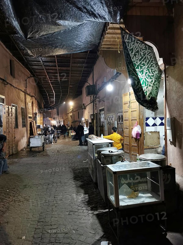 Nocturnal market alley of an oriental medina with stalls and cozy lighting, Marrakech, Morocco