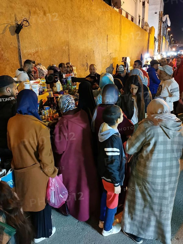 Crowd of people in thick clothing gathered on busy street in the evening, Medina of Casablanca, Marakesh