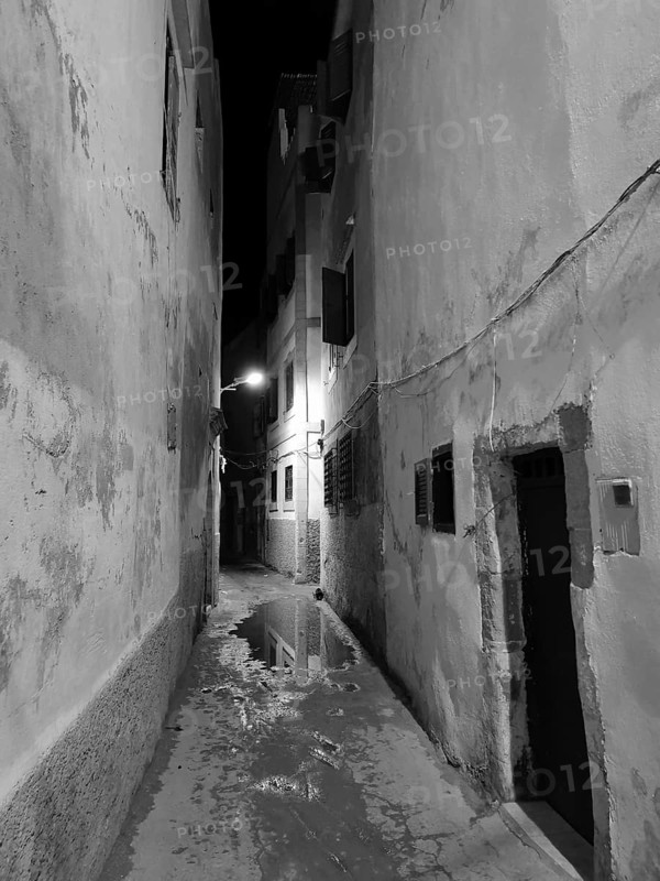 Narrow alley at night with wet floor and atmospheric lighting, monochrome, old town of Essaouira, Morocco