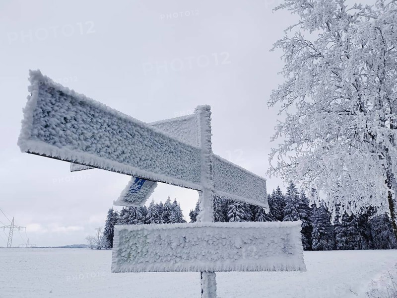 Icy trail sign covered with snow in a snowy winter landscape, Rennsteig, Frankenwald nature park Park