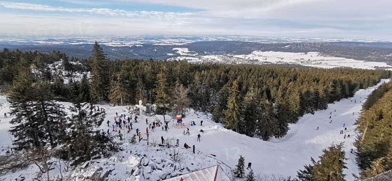 Winter landscape with snow-covered forest and people skiing, ski lift at Ochsenkopf, Fichtelgebirge