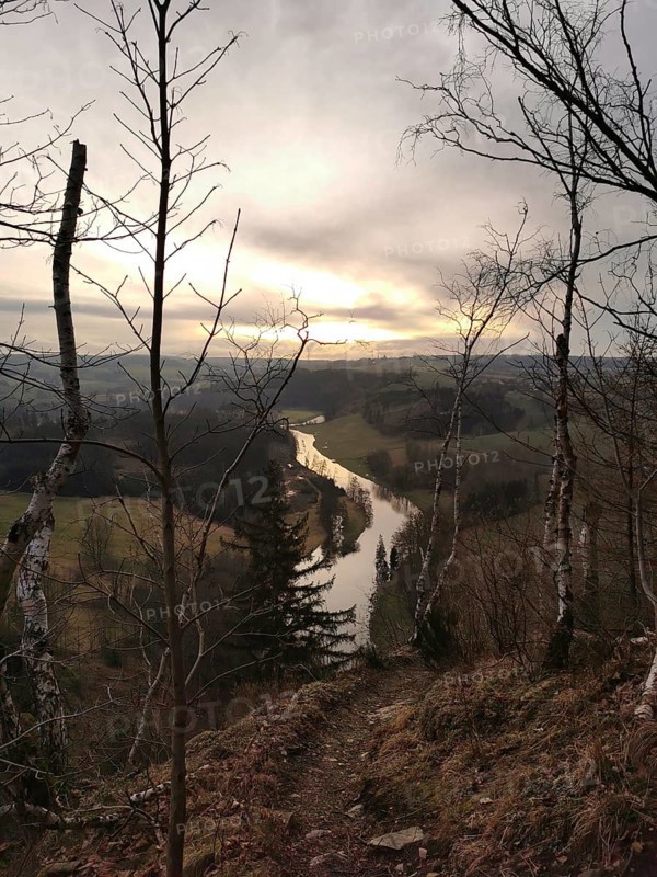 A river snakes through a hilly landscape at sunset, looking across the Saxon Saale from the Petersgratblick viewpoint, Thuringia