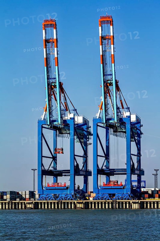 Two blue harbor cranes shine under a clear sky over calm water, The cranes of the Bremen industrial port