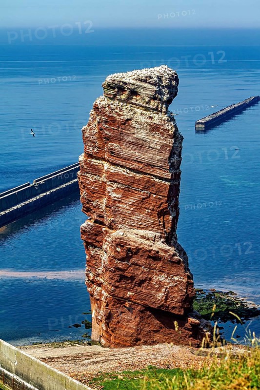 Isolated rock by the sea with a harbor wall in the background, the high-seas island of Heligoland in the North Sea