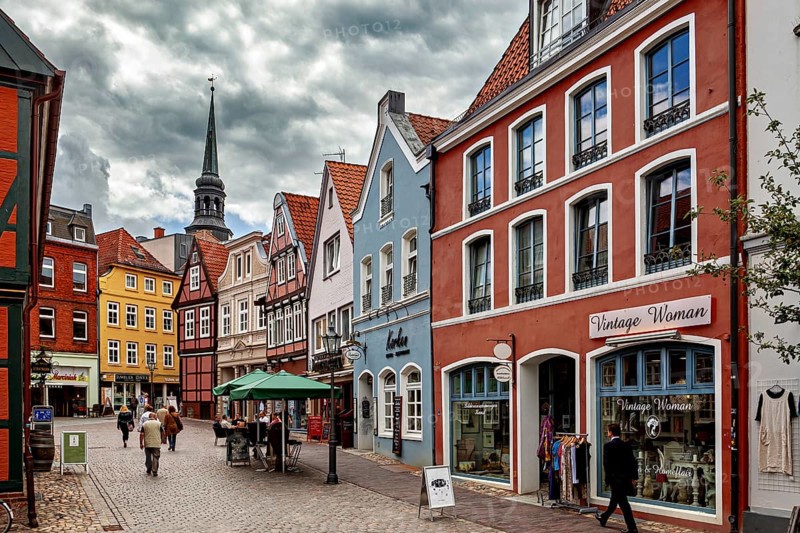 Historic street with colorful half-timbered houses and shop windows under a cloudy sky, The old town of Stade