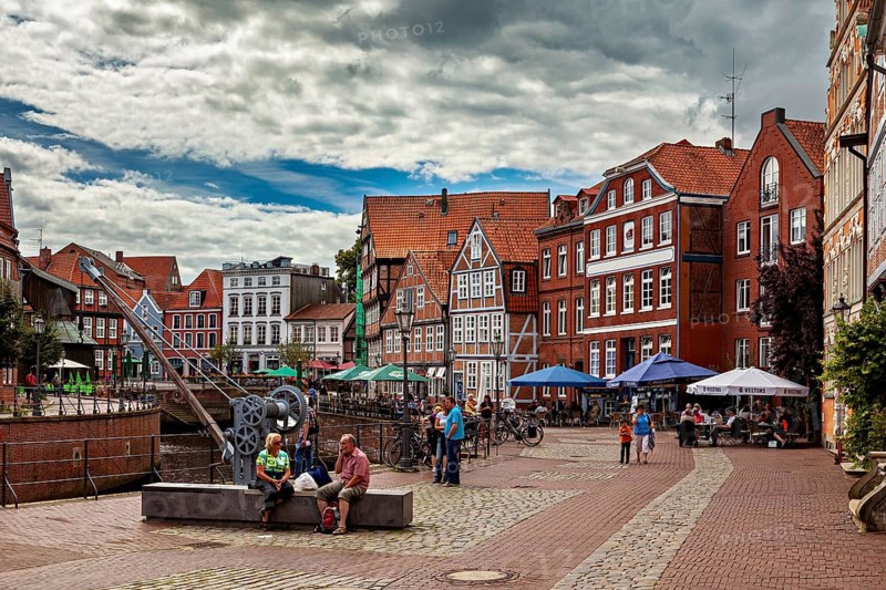 People sitting on cafe terraces along the river under a cloudy sky, The old town of Stade