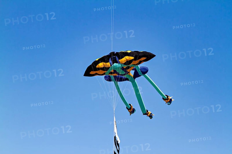 A colorful kite flies high in the blue sky under clear weather conditions, a kite in the air