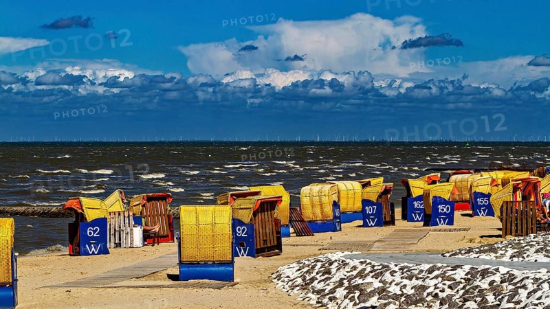 Several beach chairs along a windy beach with dramatic sky in the background, beach chairs on Cuxhaven beach