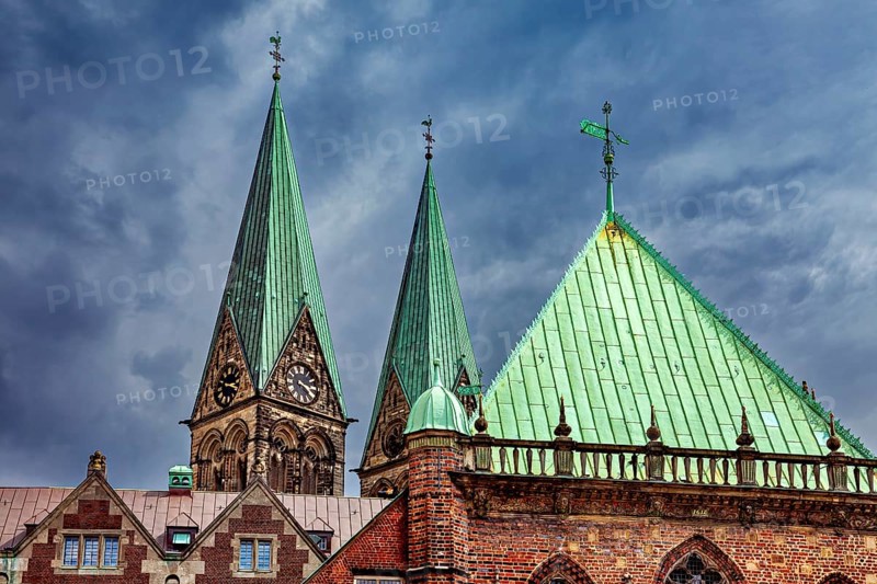 Gothic church towers with green roofs rise against a dramatic cloudy sky, The center of the Hanseatic City of Bremen