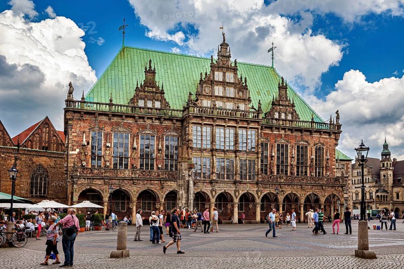 Renaissance town hall with lively hustle and bustle on the paving stone square under a cloud cover, The Bremen City Hall
