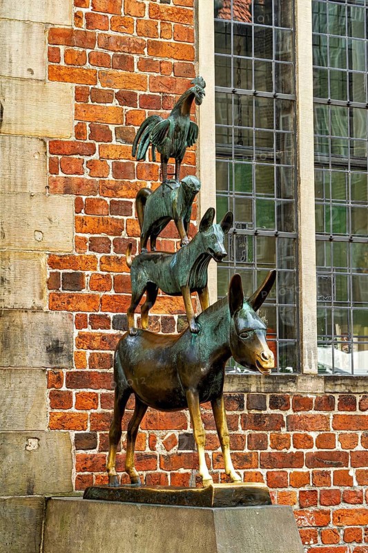 The Town Musicians of Bremen as a bronze sculpture in front of an old wall with windows, The Bremen Town Musicians Memorial in Bremen