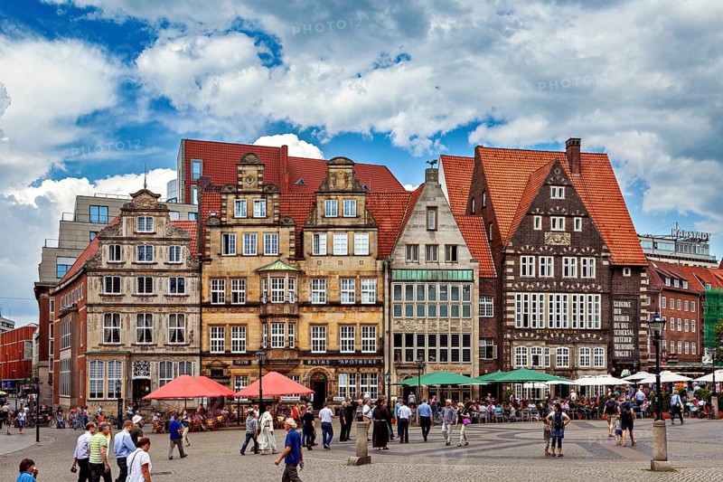 Historic old town with half-timbered houses and people on a busy market square under a blue sky, the center of the Hanseatic City of Bremen