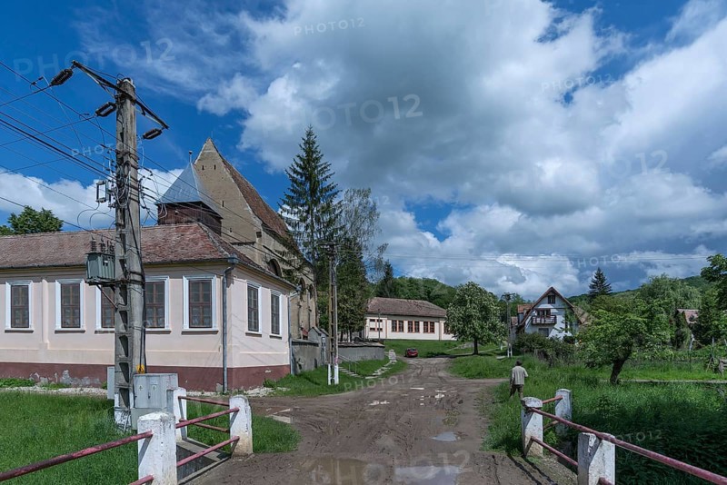 Village street with abandoned 16th century Lutheran fortified church in Tobsdorf, Romanian Dupus, —Transylvania, Romania