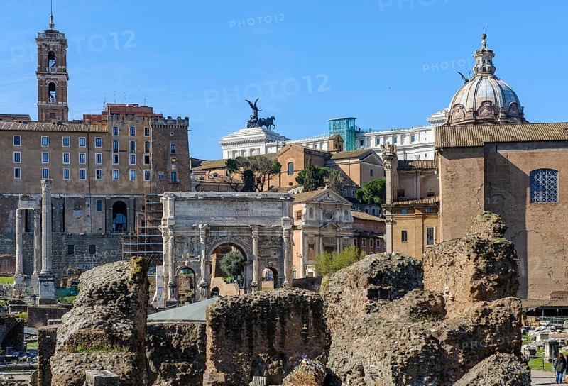 View of Roman Forum, in front ruin of temple of the Divine Caesar Julius Caesar, behind in the middle Severus Arch triumphal arch of Severus, right next to former state prison Carcer Tullianus, left back administration building of Rome Tabularium on Capitol Hill, on the edge of the picture right part of the Curia Iulia Assembly Building, in the middle back on the horizon roof terrace of the National Monument to King Victor Emmanuel II Vittoriano Altare della Patria, Parco archeologico del Colosseo, Rome, Lazio, Italy